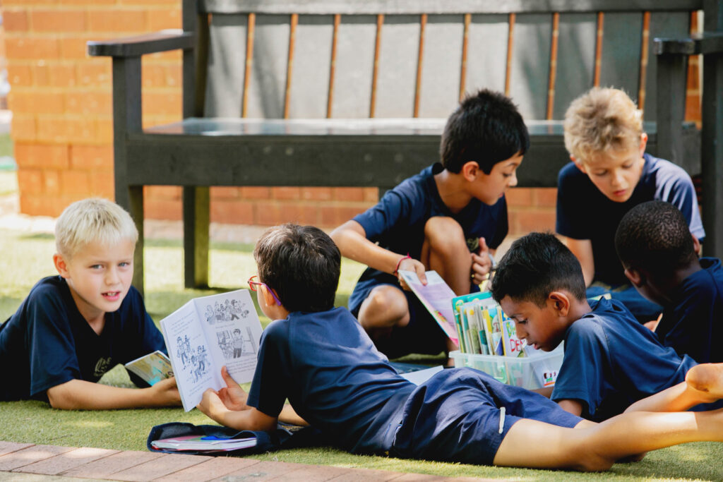 Primary school boys reading outside